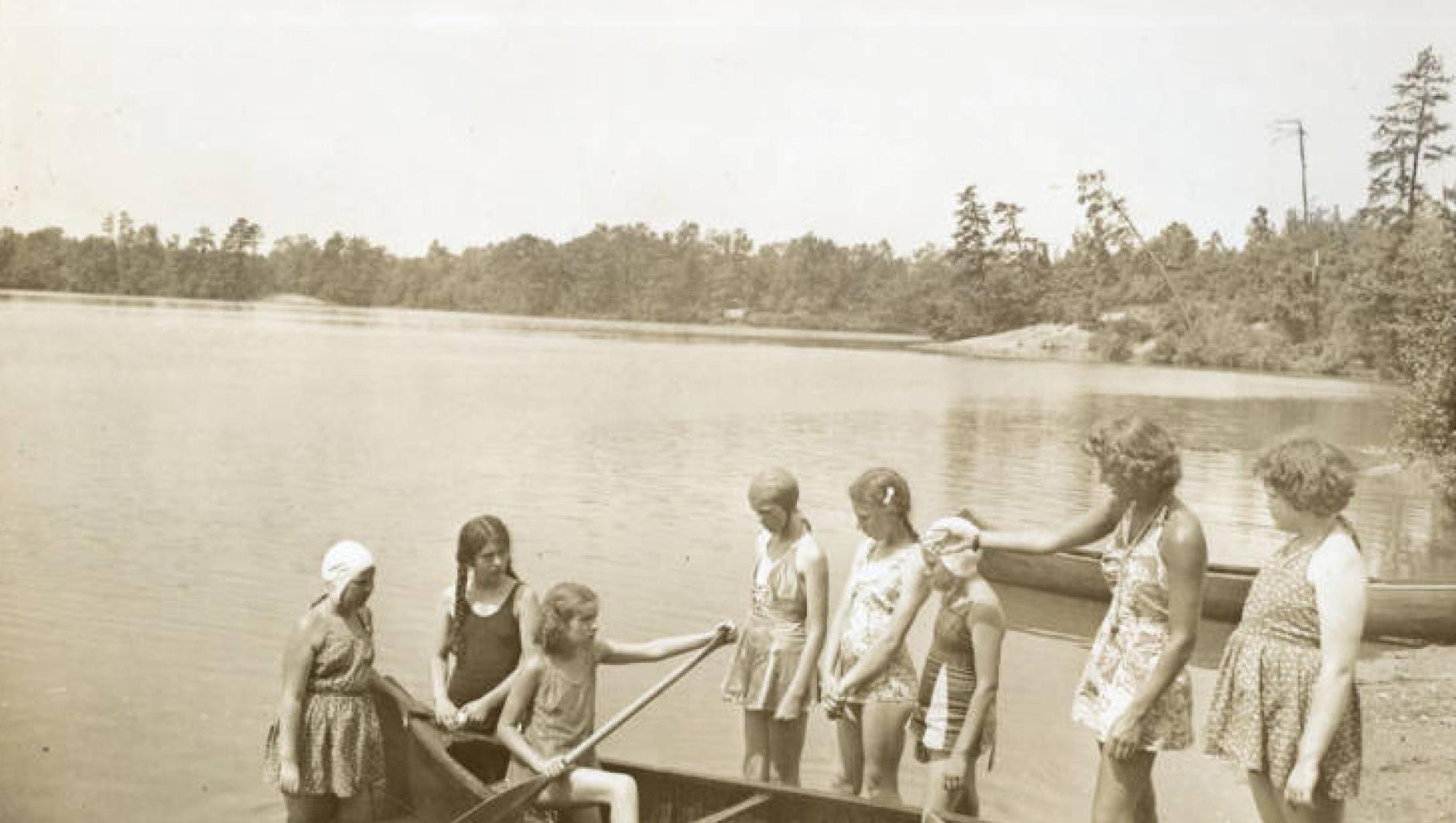 Girls get into a canoe on Camp Massasoit. 