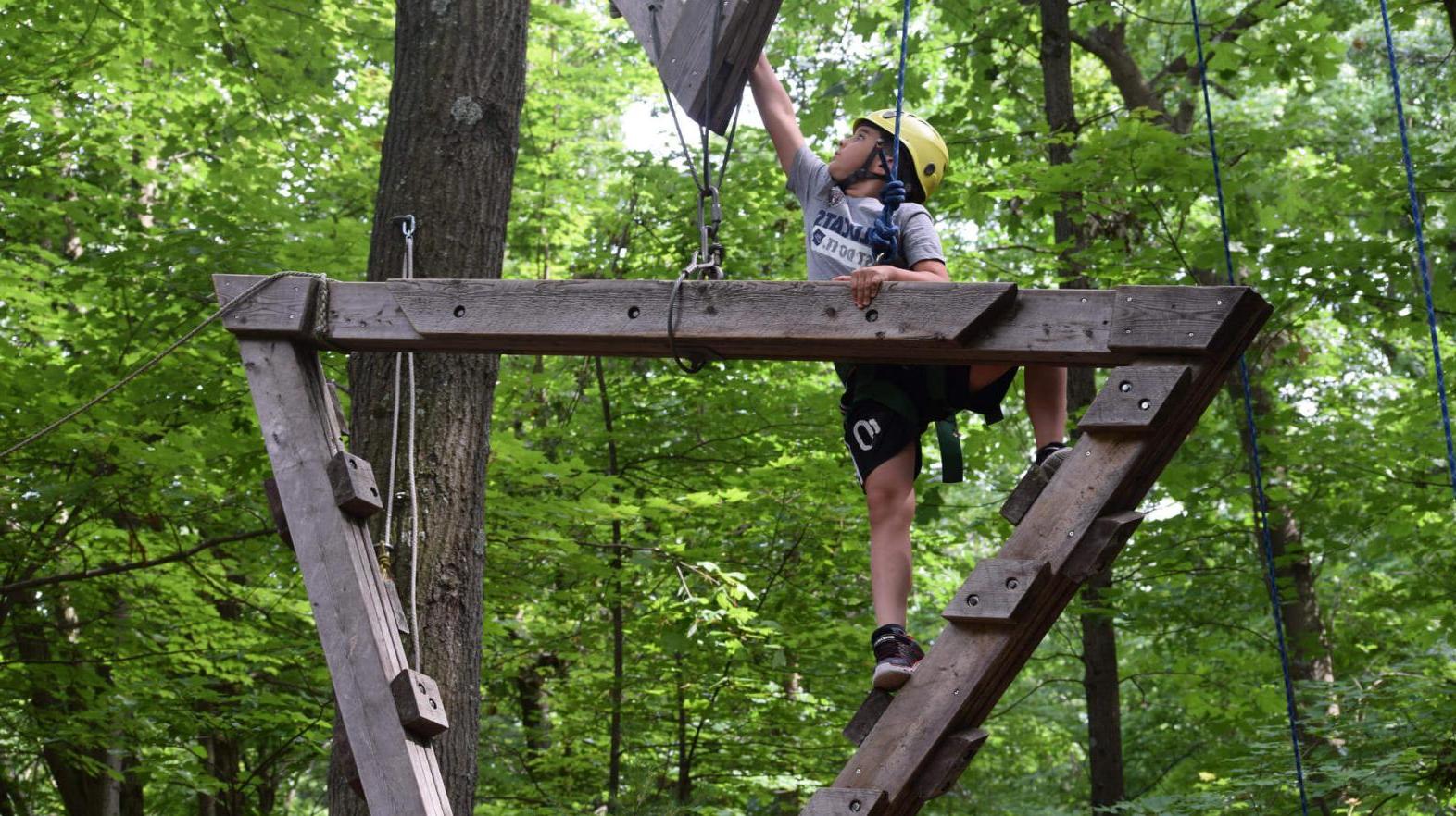 A camper climbs the rope course. 